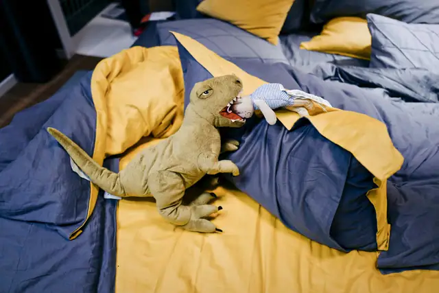 Plush T. rex on a bed